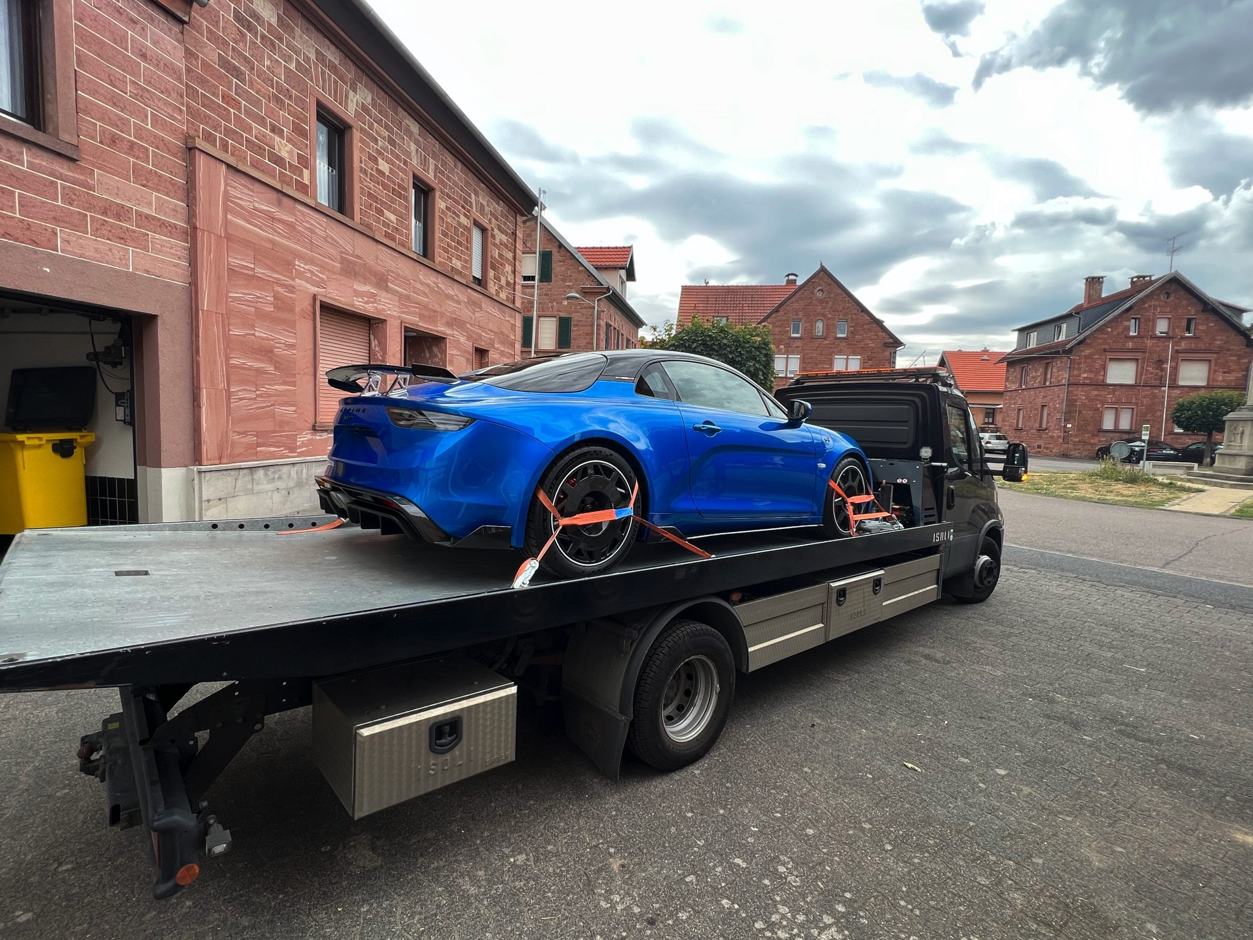 Blauer Sportwagen auf offenem Fahrzeugtransporter